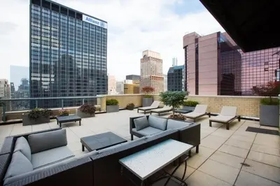 a rooftop patio with couches and tables and a city skyline at Modern Bright Times Sq 1BR w Indoor pool NYC-8 in New York