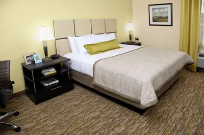 a hotel room with a large bed and a night stand at Candlewood Suites Sayre by IHG in Sayre