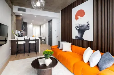 a living room with an orange couch and a kitchen at Stunning 2BD Penthouse in Chelsea w Washer and Dryer in New York