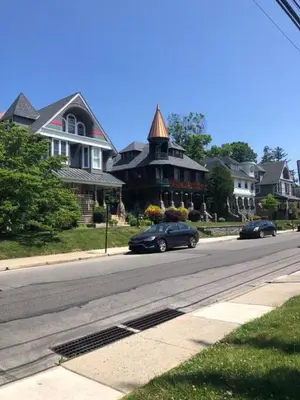 two cars driving down a street in front of houses at 5 Star Penthouse King Deck AC Train in Narberth