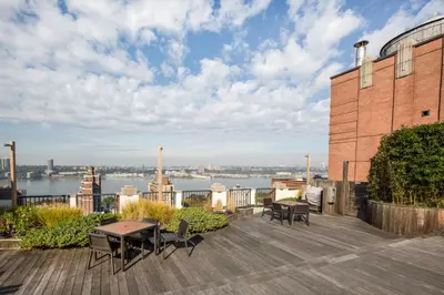 a patio with tables and chairs on top of a building at UWS 2BR w Elevator Gym DM Playroom Rooftop NYC-868 in New York