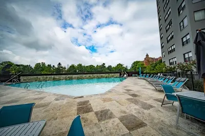 a large swimming pool with blue chairs next to a building at Avenue A310 Furnished 2br With Pool And Gym in Philadelphia