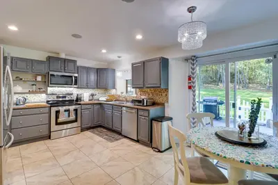 a kitchen with gray cabinets and a table and a dining room at Hot Tub, Deck and Game Room Spacious Poconos Escape in Stroudsburg