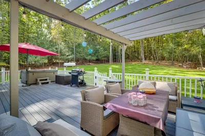 a patio with a table and chairs on a deck at Hot Tub, Deck and Game Room Spacious Poconos Escape in Stroudsburg