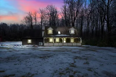 a house with lights on in a yard with snow at Log Cabin and Guest House Sleeps 18 2 Game Rooms in Long Pond