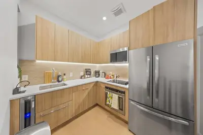 a kitchen with a stainless steel refrigerator and wooden cabinets at Private Room with Shared Bathroom at an Apartment by Times Square in New York