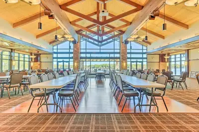 a dining hall with tables and chairs and windows at Arrowhead Lake Retreat with Private Indoor Pool! in Pocono Lake