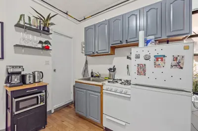 a kitchen with gray cabinets and a refrigerator at Heart of Downtown Manhattan - Stylish One Bedroom Apartment in Vibrant Union Square in New York