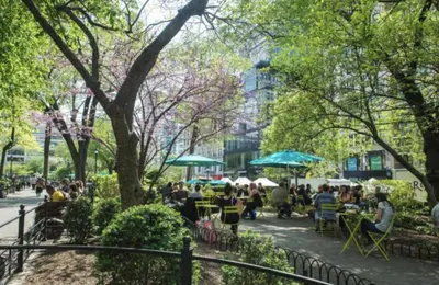 a group of people sitting at tables in a park at Private Room at a shared Apartment at the Heart of East Village in New York