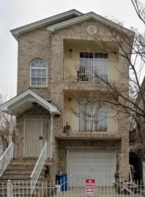 a brick house with a balcony and a garage at Room K Divine Villa and Resorts 5mins to EWR Airport and 4mins to Penn Station Newark, New York in Newark