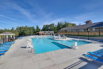 a large swimming pool with blue chairs and a building at Spacious Retreat 7 Mi to Tobyhanna State Park! in Tobyhanna