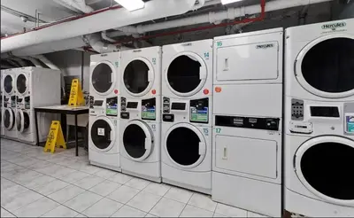 a row of washing machines in a laundry room at 73-410 Luxury 24 DM New Studio UWS Gym Laundry in New York