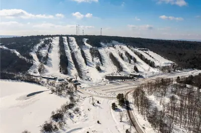 an aerial view of a snow covered hill with trees at Marvel at Midlake in Lake Harmony