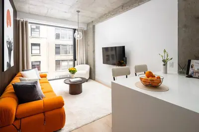 a living room with an orange couch and a kitchen at Luxury Full Floor Chelsea Apt St 7 in New York