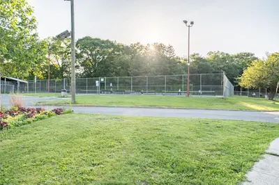 a park with a fence and a tennis court at Jetted Tub Stay in Passaic