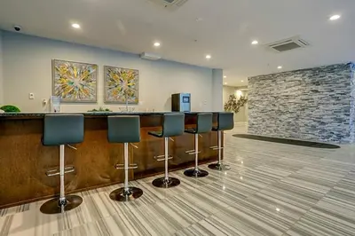 a lobby with a bar with stools and a stone wall at Glam Flat with View, Pool, Deck in Philadelphia