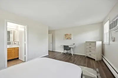 a white bedroom with a bed and a desk at Pine Brook 1202 I Pool Gym I Free Parking ! in Newark