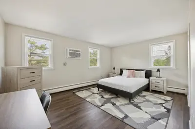 a bedroom with a bed and a dresser and two windows at Pine Brook 502 I Pool Gym I Free Parking ! in Newark