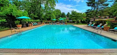 a large swimming pool with chairs and umbrellas at Pine Brook 509 I Corporate 15Br Apt I Parking in Newark