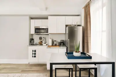 a kitchen with white cabinets and a table with chairs at 73-1406 New 1BR 1Bth UWS Doorman Gym in New York