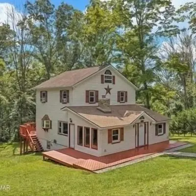 a white house with a porch on a lawn at Peaceful home in mount bethel, PA in Mount Bethel