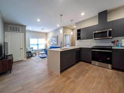 a large kitchen with black cabinets and a living room at 328 Modern 2BR Apt in Dunellen