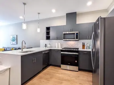 a kitchen with gray cabinets and a stainless steel refrigerator at 312 Modern 1BR Apt Walk to NJT in Dunellen