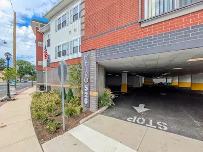 a parking lot in front of a building with a stop sign at 212 Modern 1BR Apt Walk to NJTransit in Dunellen