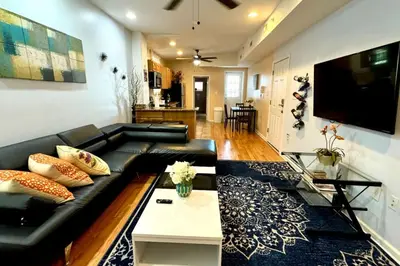 a living room with a black leather couch and a tv at Modern Cozy Huge Balcony in Heart of Passyunk in Philadelphia