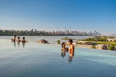 a group of people in a infinity pool with a city at Music - Big 3br with King Bd Close to EWR and NYC in Bayonne