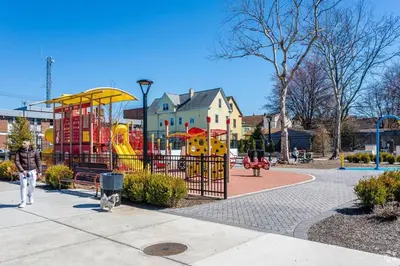 a man walking past a playground in a park at Duplex apt - Dining - 80in Projector - Pool Table in Bayonne
