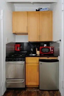 a kitchen with wooden cabinets and a red microwave at Prime Murray Hill 1BR - Near Grand Central in New York