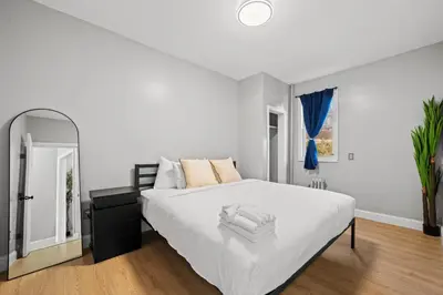 a white bedroom with a large bed and a mirror at Spacious Luxe Stay Sleeps 16 20 Min to NYC in Bayonne