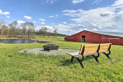 a bench sitting in the grass next to a red barn at Suite to Unwind Close to Ski Slopes in Pleasant Mount