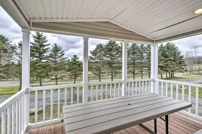 a wooden porch with a bench on a deck at The Hideout Cottage Close to Ski Mountain in Pleasant Mount