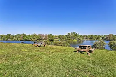 two picnic tables in a field next to a lake at Fire Pit and Game Room Spacious Poconos Retreat! in Long Pond