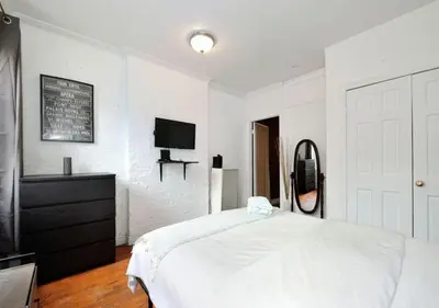 a white bedroom with a bed and a tv at Furnished 2 Bedroom Apartment Midtown West NYC, June To Aug 90 Days Stay Required in New York