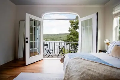 a bedroom with a bed and an open door to a balcony at Lakeview Villa with Private Hot Tub, Firepit & Breathtaking Cliff Views in Greenwood Lake