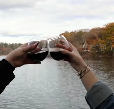 two people holding glasses of wine in front of a lake at Lakeside Haven, a Modern Cottage with Lake Views in Effort