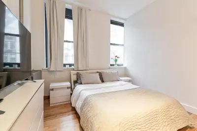 a white bedroom with a bed and two windows at XL Prime Tribeca Furnished Loft in New York
