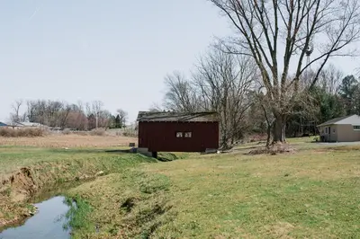 a barn in a field next to a pond at Beaver Creek Cabin 5 in Strasburg