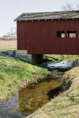a red bridge over a stream in a field at Beaver Creek Cabin 6 in Strasburg