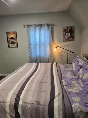 a bedroom with a bed with a striped blanket and a window at favour family house in Newark