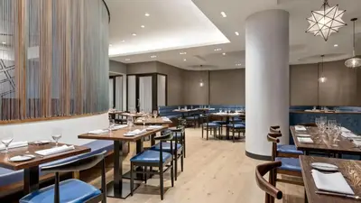 a restaurant with wooden tables and blue chairs at The Vibe on 5th XIII Vibe 8762 in New York