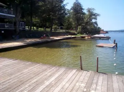 a lake with a dock and a boat in the water at Cozy Rustic Cabin Rental on Shore of Harveys Lake in Luzerne County, Pennsylvania in Harveys Lake