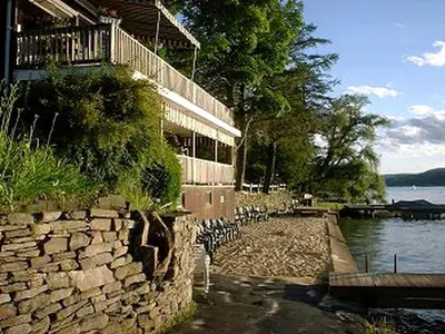 a building with a stone wall next to a body of water at Cozy Rustic Cabin Rental on Shore of Harveys Lake in Luzerne County, Pennsylvania in Harveys Lake