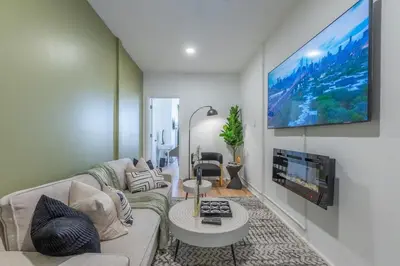 a living room with a couch and a tv on a wall at City Escape with 2 Baths, 10 beds and We Pay Half Parking for 2 cars, NYC in 15 min in Hoboken