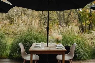 a wooden table with two chairs and an umbrella at Coop 003 in Kenoza Lake
