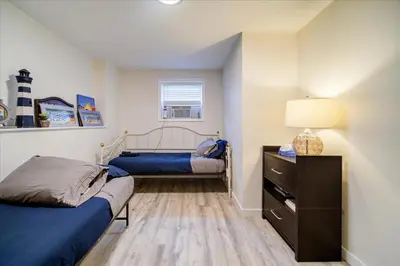 a bedroom with two beds and a dresser with a lamp at Catskills Lakefront with Hot Tub, Sauna and Theater in Monticello