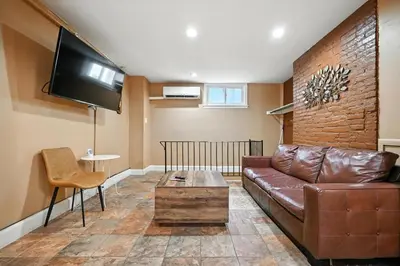 a living room with a brown leather couch and a tv at Heart of Downtown Delight in Philadelphia